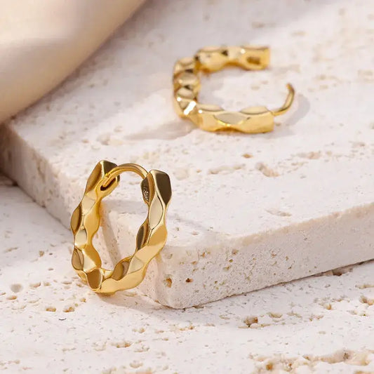 Side close-up of simple gold-plated earrings showing smooth finish