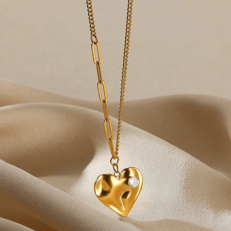 Heart-Shaped Pendant Necklace – Gold Plated Titanium Steel on elegant fabric background.