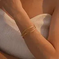 Close-up of gold-plated sea wave bangle showing wave pattern and polished finish