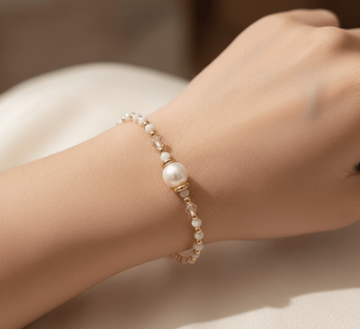 18K gold plated charm bracelet featuring pearls and soft clay charms, worn elegantly on a woman's wrist.