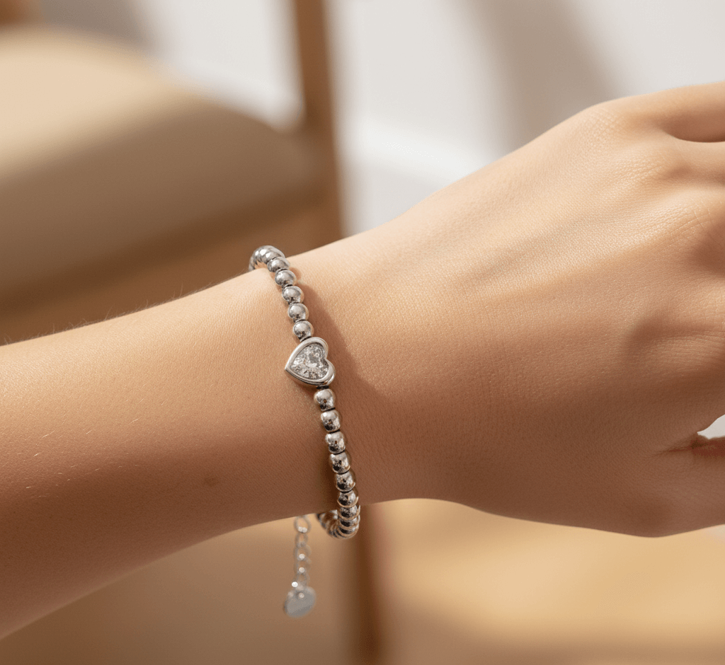 Love bead silver bracelet worn on a wrist, showcasing elegant design with heart charm and silver beads.