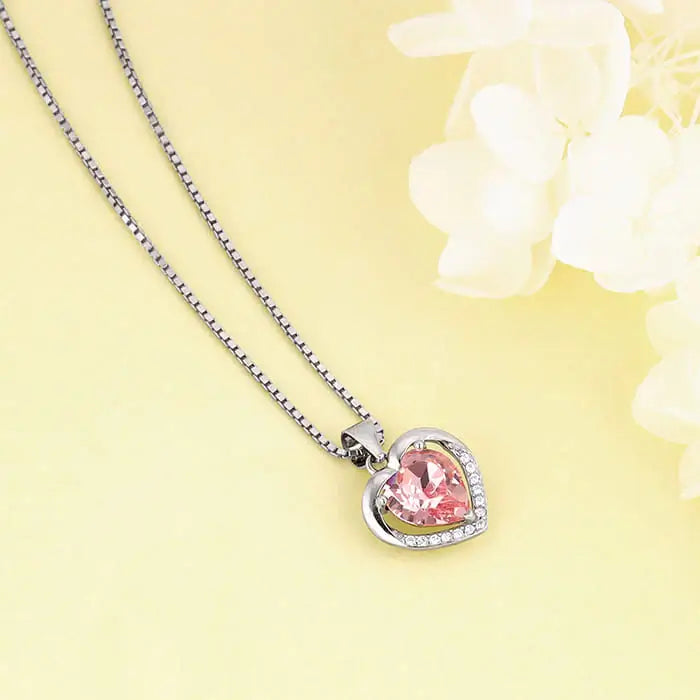 Silver heart pendant necklace with pink gemstone, set in a delicate chain.