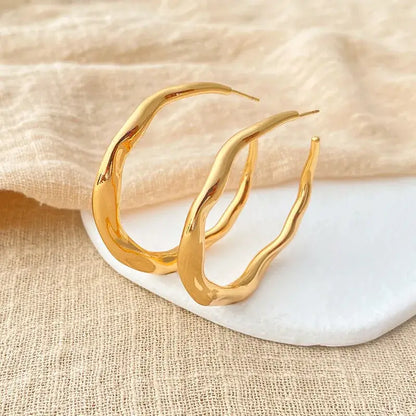 Woman wearing irregular copper stud earrings with minimalist outfit