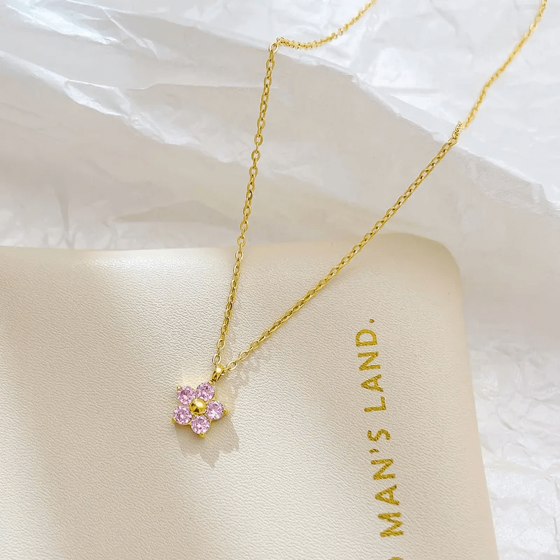 18K gold-plated flower pendant necklace on a soft surface, showcasing its elegant design and pink accents.