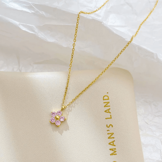 18K gold-plated flower pendant necklace on a soft surface, showcasing its elegant design and pink accents.