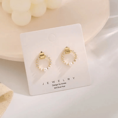 Pearl rhinestone shell earrings displayed on a jewelry card featuring gold and silver elements.