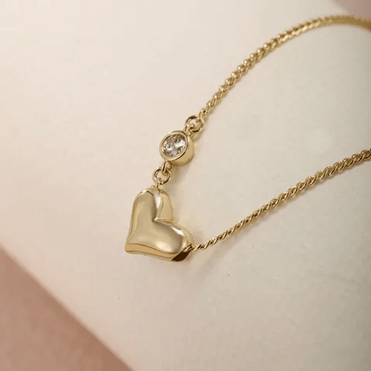 Heart shape gemstone necklace featuring a gold alloy chain and sparkling artificial gemstone accent.