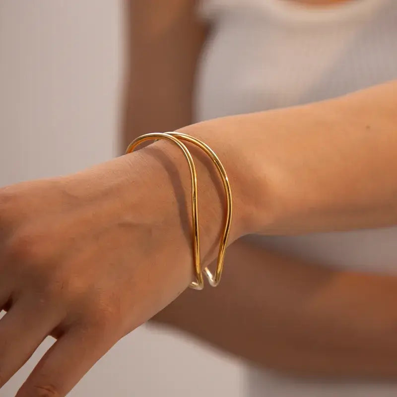 Woman wearing gold-plated sea wave bangle with elegant outfit