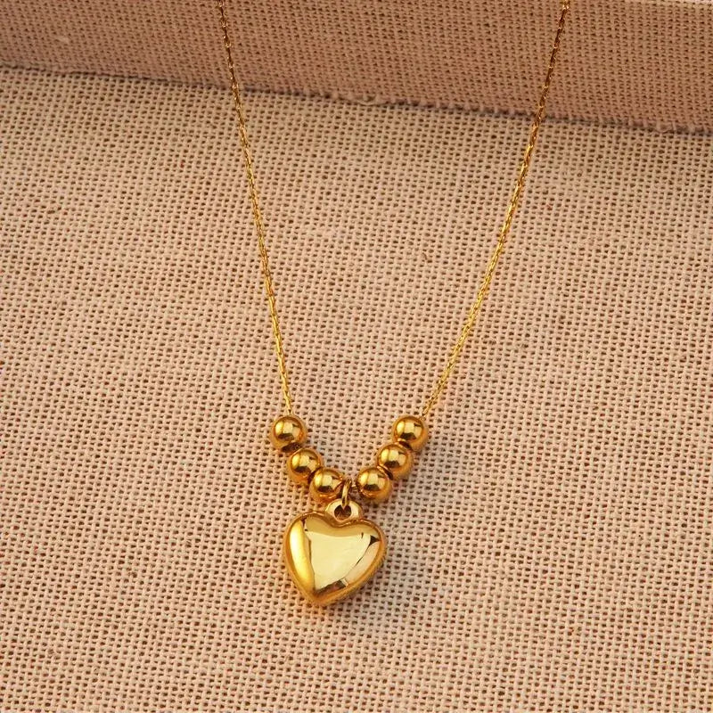 Gold heart pendant necklace displayed on jewelry stand