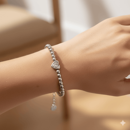 Love bead silver bracelet worn on a wrist, showcasing elegant design with heart charm and silver beads.